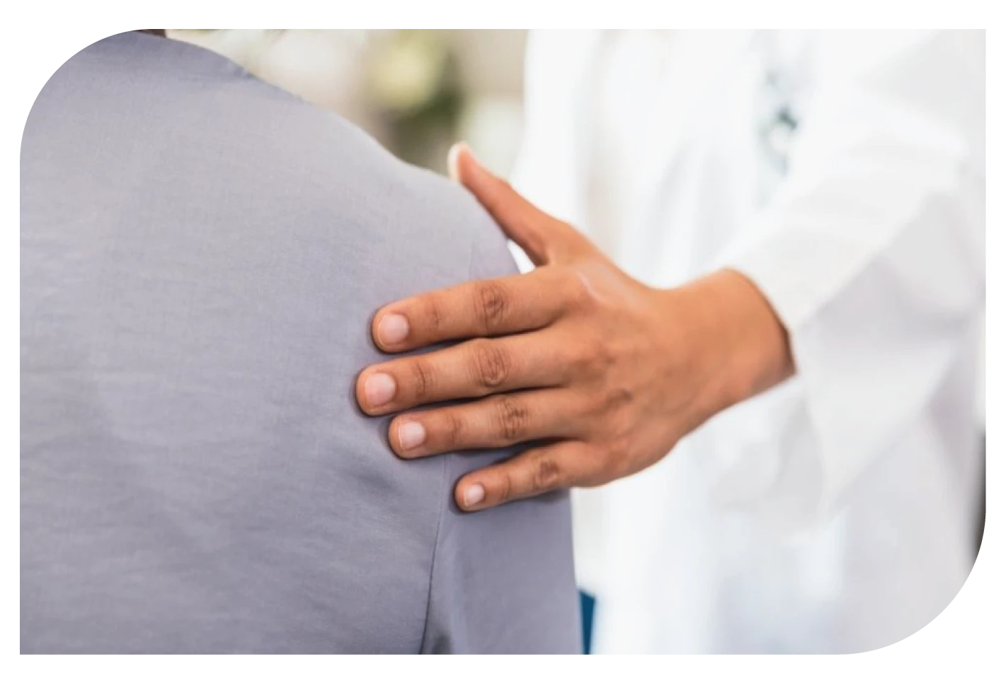 A doctor providing comforting support to a patient by placing a hand on their shoulder.